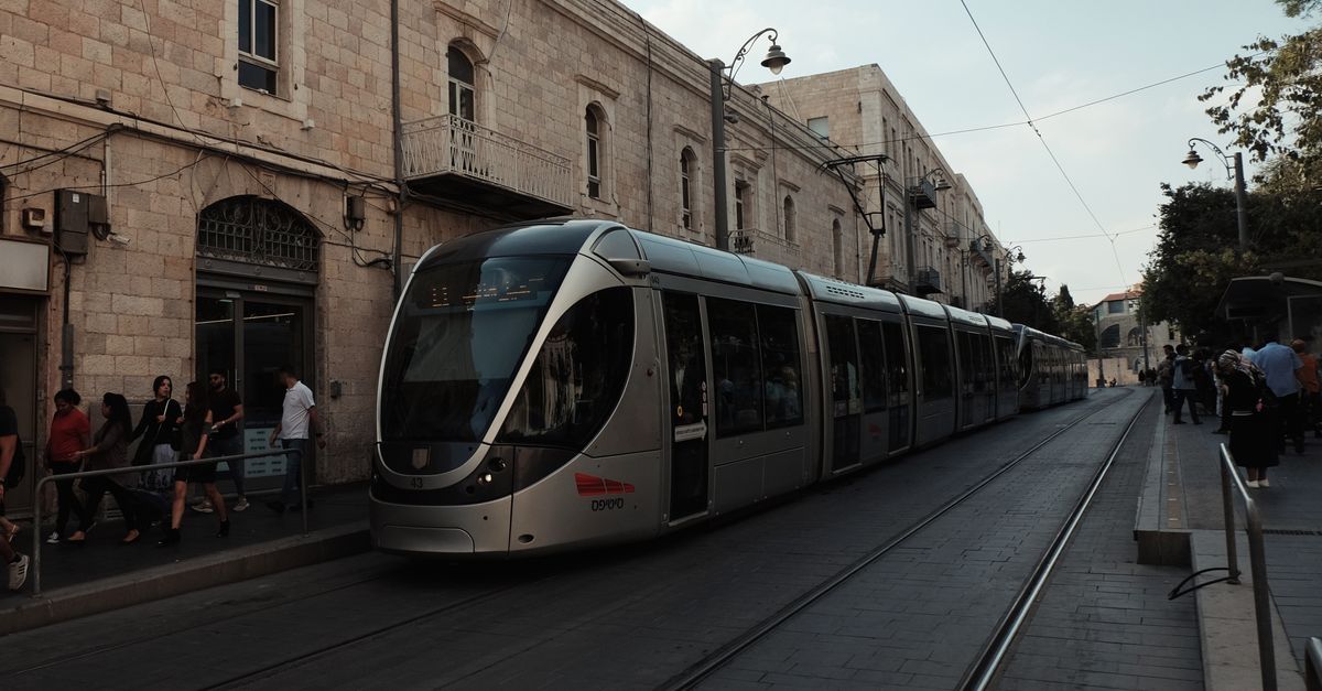 A modern tram travels through a historic city street, blending old architecture with urban transit.